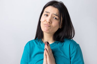 Çaresiz yüzlü güzel bir kız, yardım istiyor, avuç içlerini birbirine bastırıyor..