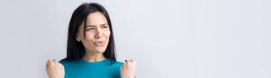 Çekici bağırışların yakın portresi. Genç yaşta yumruklarıyla gülümsüyor. Gri arka planda izole kot gömlek giyen kız arkadaşı.