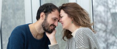 Pencereden dışarı bakan romantik bir çift. Evde karantina.