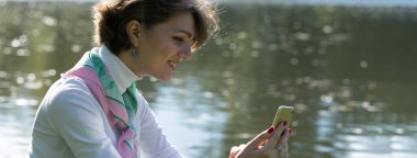 Parktaki genç kadın cep telefonuyla konuşuyor. Fransız tarzında şirin bir kız portresi..