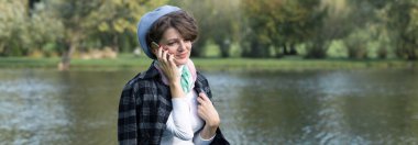 Parktaki genç kadın cep telefonuyla konuşuyor. Fransız tarzında şirin bir kız portresi..