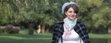 Parktaki genç kadın cep telefonuyla konuşuyor. Fransız tarzında şirin bir kız portresi..