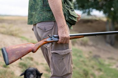 Bir avcının eline silahla yakın çekim. Silahlı bir avcının orta boy fotoğrafı..