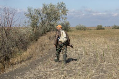 Kamuflaj kıyafeti giymiş silahlı bir avcı. Silahlı bir beyefendi, orta ölçekli, tanınmaz halde..