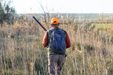 Kamuflaj kıyafeti giymiş silahlı bir avcı. Silahlı bir beyefendi, orta ölçekli, tanınmaz halde..