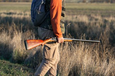 Kamuflaj kıyafeti giymiş silahlı bir avcı. Silahlı bir beyefendi, orta ölçekli, tanınmaz halde..
