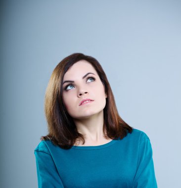 gri bir arka plan üzerinde ararken mavi tişört düşünceli kız