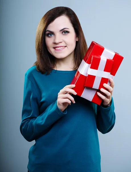 smiling young girl in a blue t-shirt holding gift boxes on gray background