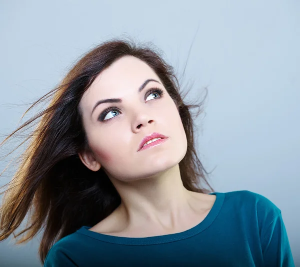 Thoughtful girl in a blue t-shirt looking up on a gray background — Stock Photo, Image