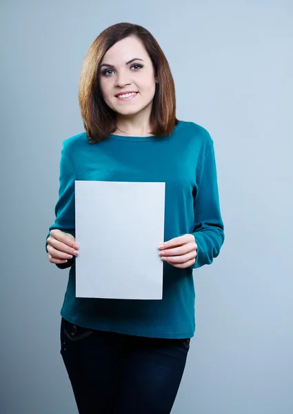 Thoughtful girl in a red T-shirt on a gray background holding a question mark — Stock Photo, Image