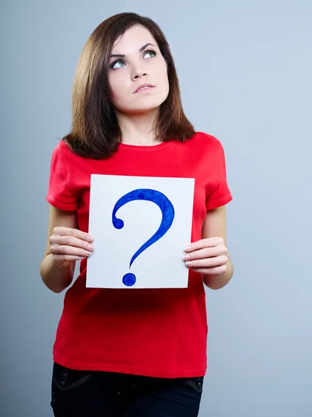 Bir soru işareti tutarak gri arka plan üzerinde kırmızı bir tişört düşünceli kız — Stok fotoğraf