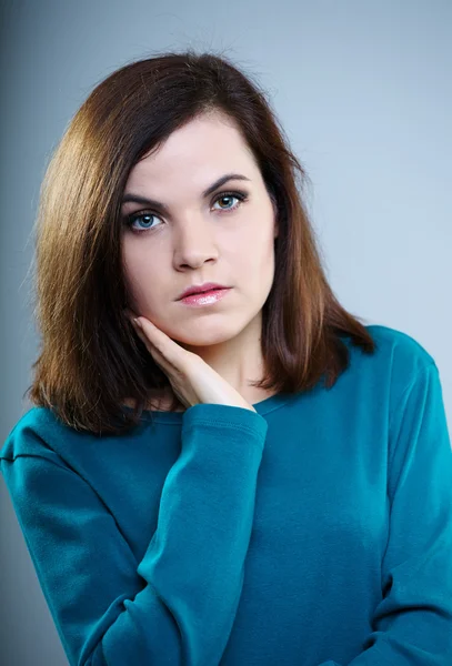Menina pensativa em uma camiseta azul olhando para cima em um fundo cinza — Fotografia de Stock