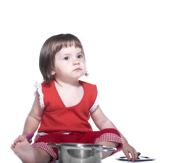 Little girl in a red suit. Playing with a saucepan and a spoon. — Stock Photo, Image