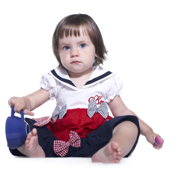 Niña en un vestido colorido sosteniendo una taza en sus manos y un —  Fotos de Stock