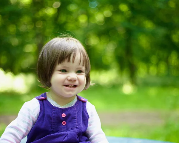 Malá usměvavá dívka v modrých šatech na přírodu — Stock fotografie