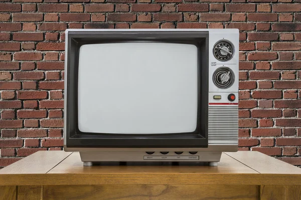 老式的便携式电视和红砖墙的表 — 图库照片