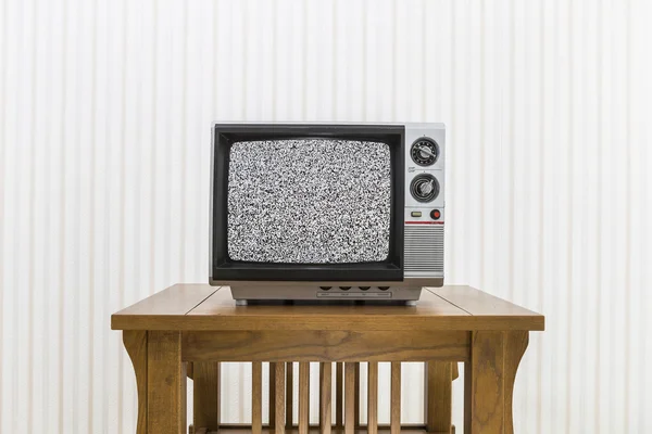 Televisión portátil antigua en mesa de madera con pantalla estática — Foto de Stock