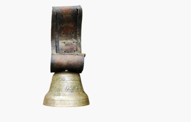 Büyük bir antika pirinç inek çanı, deri kayışlı, beyaz arka planda izole edilmiş.