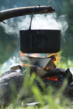 Su dolu tencere, kamp ateşinin üzerinde asılı duruyor.