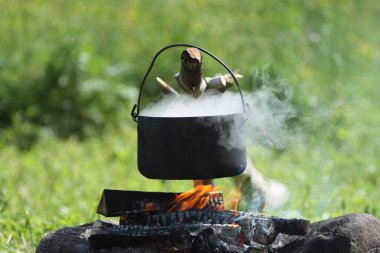 Su dolu tencere, kamp ateşinin üzerinde asılı duruyor.