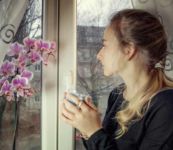 Портрет застенчивой женщины, глядящей в мокрое окно — стоковое фото