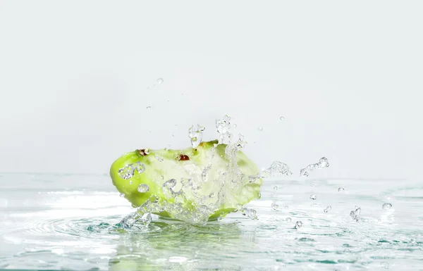 Szelet almát a víz csobbanás. Tónusú kép — Stock Fotó