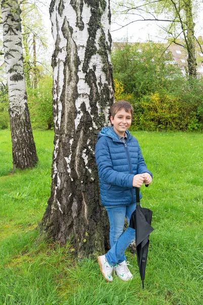 Utomhus porträtt av bedårande pojke med paraply under regn — Stockfoto