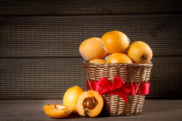 Loquats dans le panier sur fond en bois — Photo