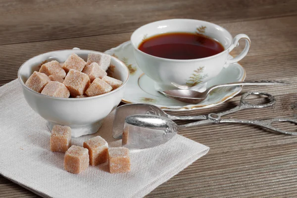 Hnědý kusový cukr a šálek čaje — Stock fotografie