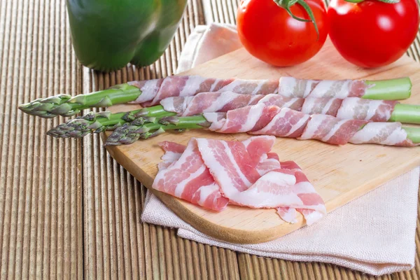 Bacon and asparagus on a wooden background — Stock Photo, Image