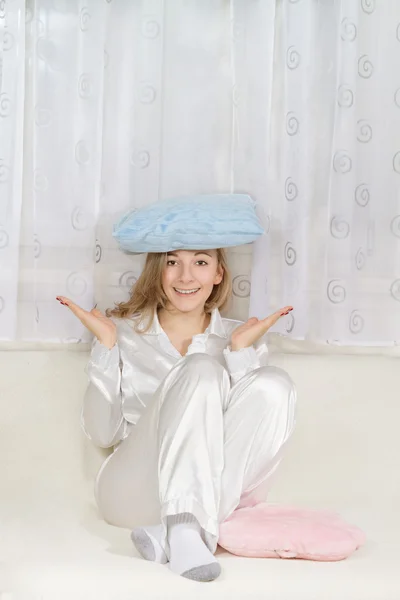 Young woman in pajamas sitting and holding pillow — Stock Photo, Image