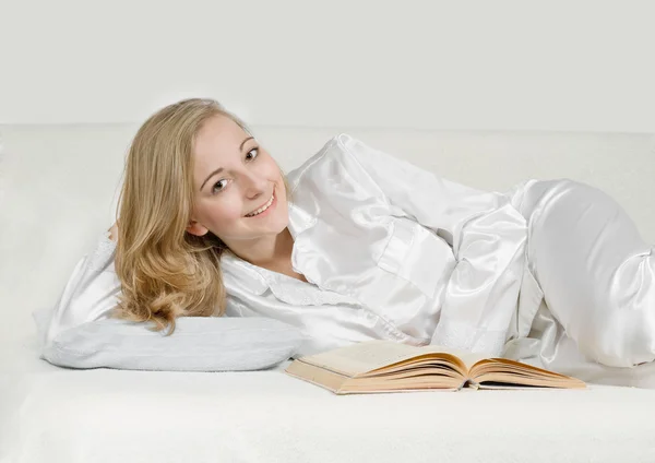 Jonge vrouw leest een boek in bed — Stockfoto