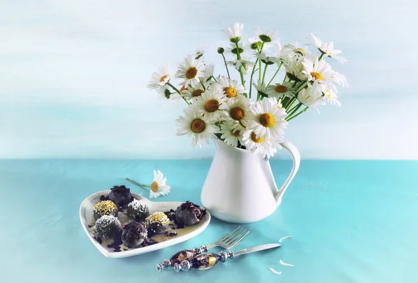 Nature morte avec des chocolats et un bouquet de marguerites sur une ba bleue — Photo