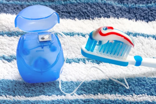 Dental floss and a blue toothbrush on a towel — Stock Photo, Image