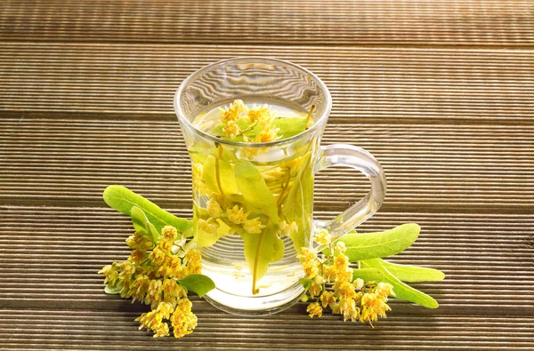 Verre de thé aux fleurs de tilleul sur fond bois — Photo