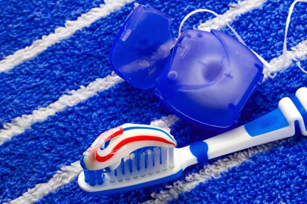Dental floss and a blue toothbrush on a towel, — Stock Photo, Image