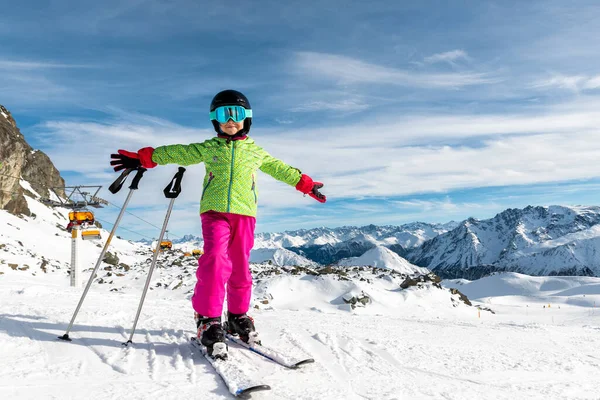 Aktiva bedårande förskolebarn kaukasiska flicka porträtt med ski i hjälm, glasögon och ljusa kostym njuta av vinter extrema sportaktiviteter. Liten barnskidåkning på lyxig alpin resort i bergen — Stockfoto