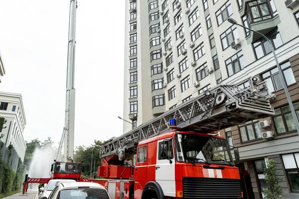 Molti camion dei pompieri con scala e attrezzature di sicurezza in caso di incidente in grattacielo appartamento residenziale o edificio per uffici nel centro della città. Soccorso di emergenza in caso di catastrofe — Foto Stock