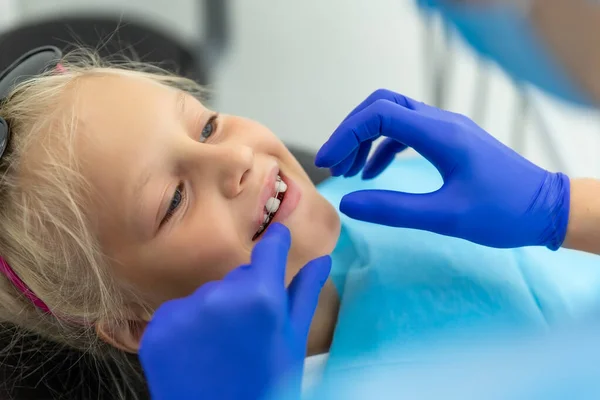 Klein schattig gelukkig blank blond meisje op tandartspraktijk bij tandarts check-up van tandheelkundige beugels. Kind tijdens orthodontist bezoek en mondholte behandeling. Kinderen tandverzorging en hygiëne — Stockfoto