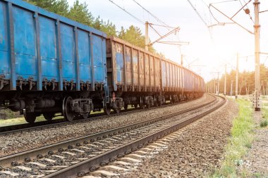 Ağır kargo, paslı tren vagonları gün batımında ya da gün doğumunda demiryolunda hareket ediyor. Endüstriyel malzeme taşımacılığı ve mal teslimatı kavramı. Eski paslı vagonlar demiryolu ile hareket ediyor.