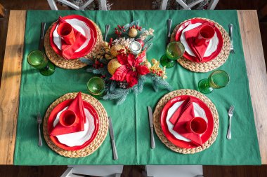 Arka planda ışık ve noel ağacı dallarında mum bulunan 4 kişiye sunulan bayramlık Noel Xmas aile sofrasının düz manzarası vardı. Basit, sıcak, kırsal bir yeni yıl arifesi yemek dekorasyonu.