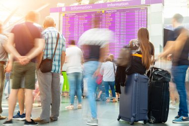 Hareket bulanık gezginler, havaalanı uçak ya da tren terminalinde gidiş ve varış saatlerine bakıyorlar. Seyahat ve turizm konsepti. Uçuş ertelenmesi. Covid-19 salgını tecrit