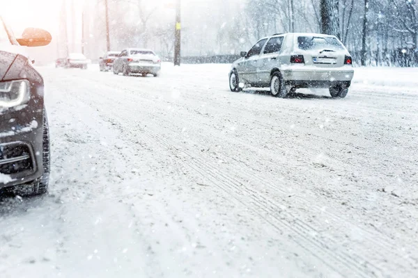 Los coches que se mueven en el camino resbaladizo nevado en la calle de la ciudad durante las fuertes nevadas en la noche en invierno. Obstáculo de tráfico debido a ventisca y tormenta de nieve. Pronóstico tiempo —  Fotos de Stock