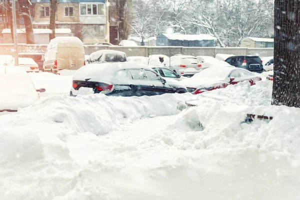 Apartamento o edificio de oficinas estacionamiento con muchos coches cubiertos de nieve escondido después de nevadas fuertes ventisca en el día de invierno. Deriva de nieve y vehículos congelados. Condiciones meteorológicas extremas —  Fotos de Stock