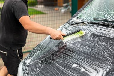 Minibüs araba yıkama, yüksek basınçlı su teçhizat pompası, açık havada, güneşli bir yaz gününde. Araba oto yıkama servisi sırasında köpük şampuanla kaplı kimyasal deterjanlar..