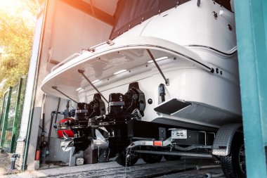 Depo teknesinin garajındaki römork rampasında lüks bir tekne kruvazörü motoru var. Gemi servisi, temizlik, onarım veya bakım konsepti. Lüks balıkçılık eğlence yaşam tarzı..
