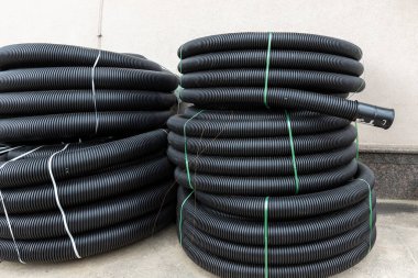 Birçok rulo yeni siyah kıvrımlı goffred plastik su boşaltma borusu inşaat alanı yakınında kurulum için hazırlandı. Kanalizasyon borusunu boşalt.