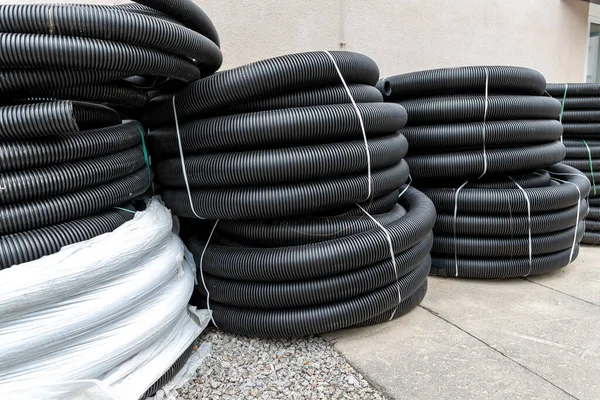 Birçok rulo yeni siyah kıvrımlı goffred plastik su boşaltma borusu inşaat alanı yakınında kurulum için hazırlandı. Kanalizasyon borusunu boşalt.