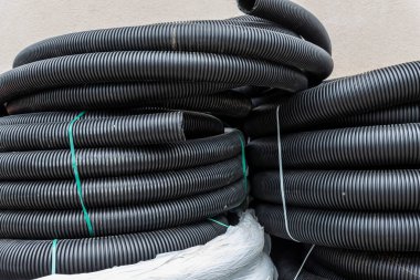 Birçok rulo yeni siyah kıvrımlı goffred plastik su boşaltma borusu inşaat alanı yakınında kurulum için hazırlandı. Kanalizasyon borusunu boşalt.