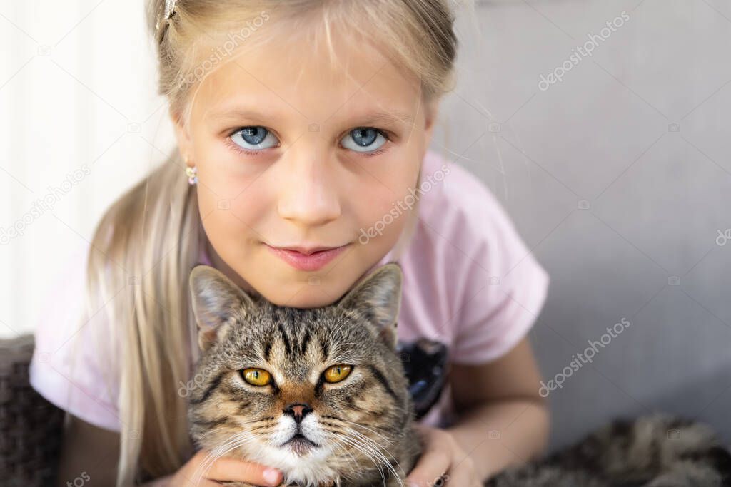 Cute adorable caucasian blond sweet little eight year girl enjoy sitting in armchair outdoor holding and hugging small napping cat in hands. Pet kitten and kid friendship concept. Animal care and love
